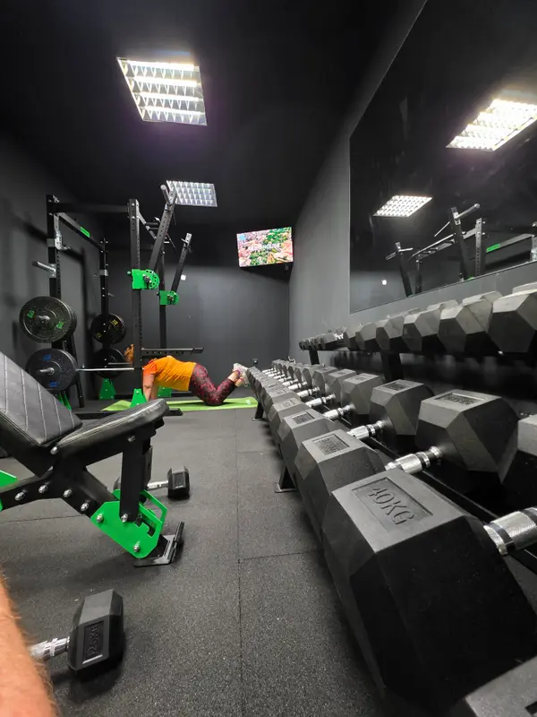Pogled na dvoranu V-Lift Small Gyma — red heksagonalnih bučica, stalci i klupe